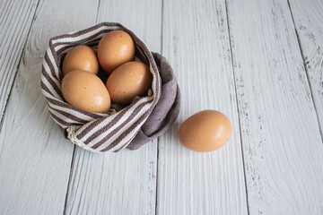 Brown chicken eggs lay on the wooden floor with brown fabric, vintage style.