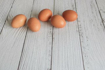 Brown chicken eggs lay on the wooden floor.