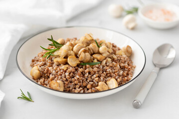 buckwheat porridge with fried mushrooms and onions in a white bowl