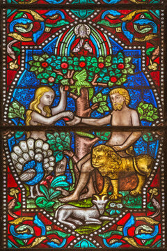 MAREDSOUS, BELGIUM - AUGUST 2015: Detail of an old stained glass window in the abbey of Maredsous. Depicted are Adam and Eve in the garden of Eden sharing an apple.