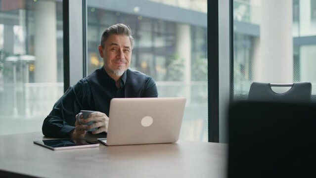 Businessman using laptop computer in office. Happy middle aged man, entrepreneur, small business owner working online.