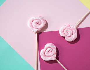 Pink lollipops in the shape of hearts on a color background. Pop art concept. Top view and copy space