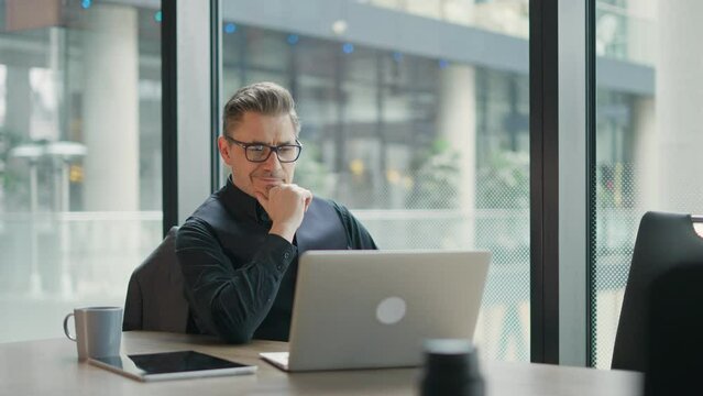 Businessman using laptop computer in office. Happy middle aged man, entrepreneur, small business owner working online.