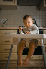 the kid is at home in the kitchen eating an egg