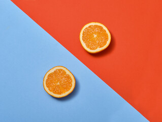 Two slices of orange on a blue and red background