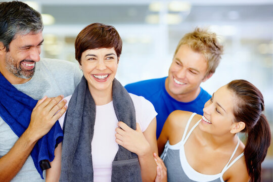 Cheerful friends at fitness center. Portrait of beautiful woman holding towel with her friends at fitness center.