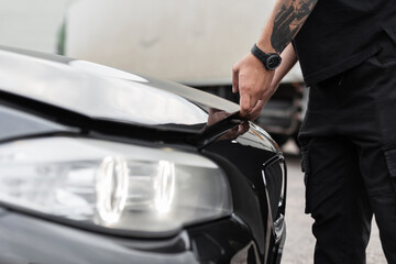 Obraz premium Man driver opens the hood of the car. Man's hands open the hood, close-up