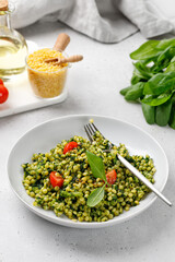 Israel couscous, green ptitim dish with spinach and broccoli, cherry tomatoes. Vegan, Traditional Israeli pasta.