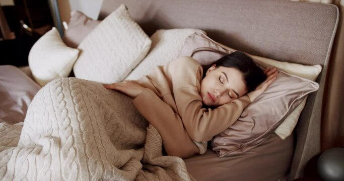 Woman sleeping in bed at the morning. Calm young woman sleeping well in comfortable cozy fresh bed on soft pillow white linen orthopedic mattress and warm duvet blanket in a cosy bed in a bedroom.