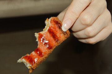 a nibbled piece of toast with jam in hand. fried bread.