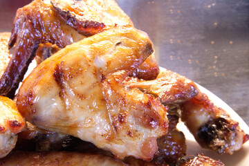 Closeup of tasty grilled chicken hot wings on a white dish, black wooden background. bbq chicken wing appetizer food