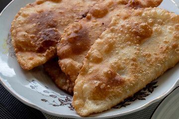 Fried pasties on a plate in sunflower oil. Fried dough with meat in oil.