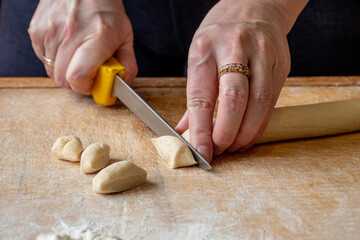 Cutting raw dough in flour with a knife. Close-up of woman hands cutting dough