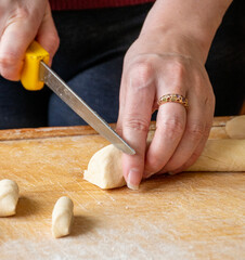 Cutting raw dough in flour with a knife. Close-up of woman hands cutting dough