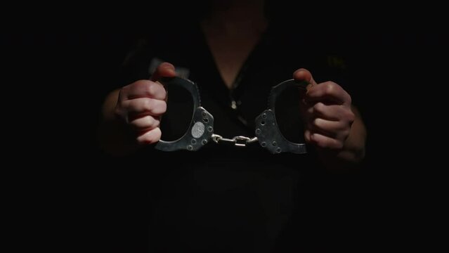 Policeman closes handcuffs holding in his hands close up. Concept of arrest sentence for crime, justice and law. 