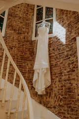composition - background old brick wall with decor and accessories a wedding dress in front of a wooden white staircase and a white window