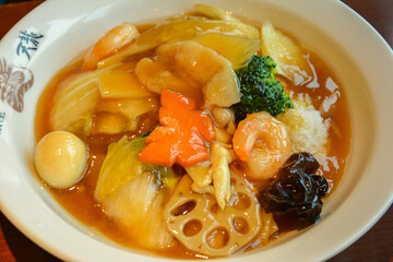 Beijing style Chinese noodle and rice soup with oyster sauce, quail egg, shrimps, broccoli, carrot and lotus root served in Chinese restaurant in Tokyo, Japan
