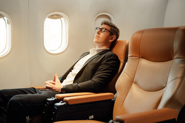 Businessman sleep while sitting in airplane, Traveling and technology. Flying at first class.