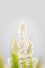 Buddhist composition with white Buddha statue on a neutral light gray background. Vesak, Buddha Day. Soft image and soft focus style. Mental health and meditation