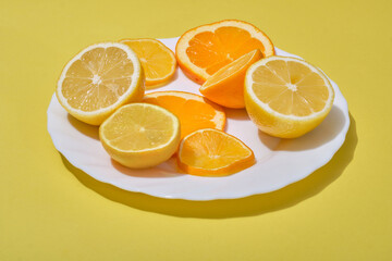 Oranges and lemons served on a plate on a yellow background