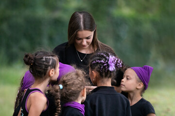 Coach of rhythmic gymnastics talking with her trainees after training outdoors