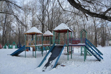 children's slides in the snow on the background of trees