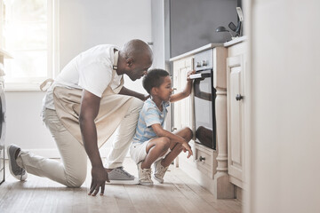 Its so much fun to mix all the ingredients. Shot of a father and son standing by the oven in the...