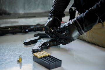 Asian male wearing black leather gloves with gun in hand,loading bullets to gun