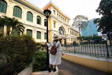 Woman tourist is sightseeing at Saigon Central Post Office. The building was constructed when Vietnam was part of French Indochina in the late 19th century.