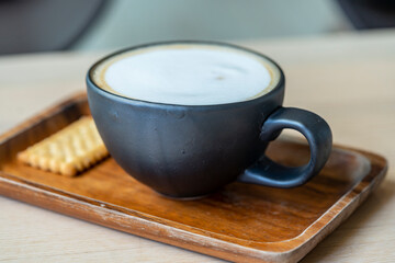 a black cappuccino coffee mug on a wooden tray. morning breakfast at the lifestyle coffee shop