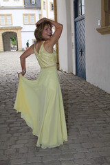 Obraz premium attractive woman in an evening dress walks through a gate in the neuhaus castle near paderborn