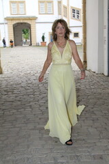 attractive woman in an evening dress walks through a gate in the neuhaus castle near paderborn