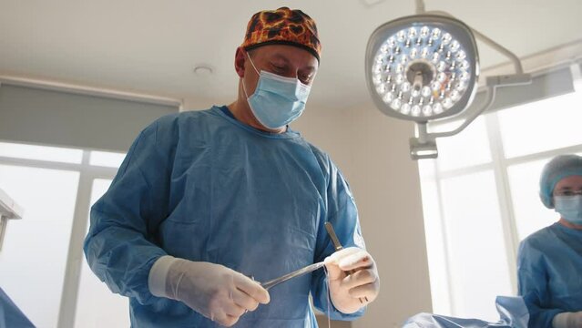 The surgeon uses a needle holder to hold the surgical needle and thread to suture the patient's skin