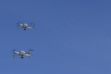 Two modern Remote Control Air Drones Fly with action cameras in blue sky. Modern technologies. Close up. Travel, hobby, inspiration.