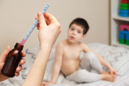 The pediatrician or mother types in a measuring syringe the medicine for cough or temperature syrup for the child