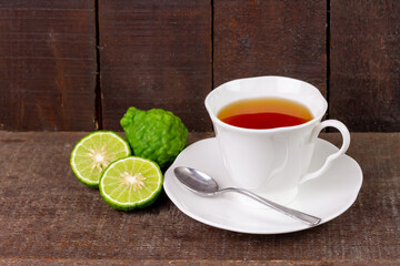 Bergamot tea or Earl Grey tea in ceramic cup and fresh bergamot fruit with sliced on brown wooden table.