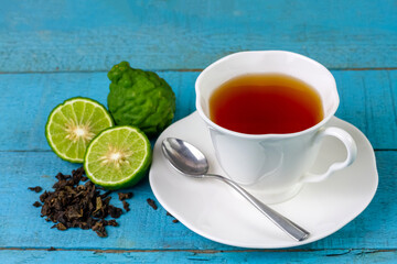 Bergamot tea or Earl Grey tea in ceramic cup and fresh bergamot fruit with sliced on blue wooden table.