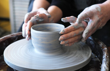 Fototapeta na wymiar Male and female hands make a vase of clay. Date in the workshop