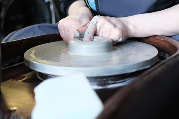 Female hands crafting a pottery cup on a potter wheel.