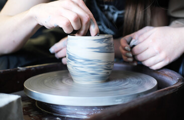 Male and female hands make a vase of clay. Date in the workshop.