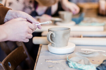 Men hands hold a paint brush to paint clay products.