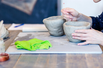 Ceramics. A sculptor makes a plate from a clay. woman potter working with clay brush