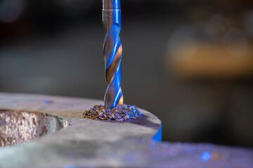 metal drill bit make holes in aluminum billet on industrial drilling machine with shavings. Metal...