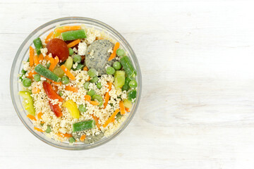 Frozen food: mix of couscous, vegetables and sauce in a glass bowl on a white table