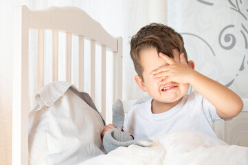 Sick three year old child sitting on bed and crying. The kid had a bad dream