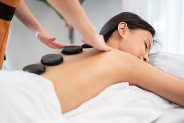 Obraz na płótnie Canvas Beautiful woman getting spa hot stone massage in the therapy room at wellness center. Masseuse or physical therapist doing massage at shoulder and neck. Girl enjoy body treatment.