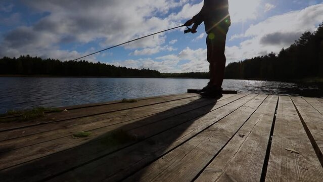 sherman fishing with reel rod, spinning with sky in clouds, lake. Twitching technique