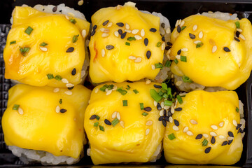 Rolls salmon, avocado, sesame seeds, cheese, green onions in a plastic container. Fast food, food delivery.