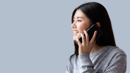 Happy Asian young woman talking on phone with smile Beautiful girl looking to copy space during talking on mobile phone with gray background Use for advertisement
Female get a conversation to someone