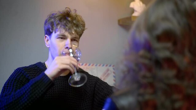 A young couple meets in a nightclub bar. The guy winces from alcohol. The couple drinks alcohol. Night club